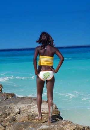Высокая негритянка в цветных трусах позирует на пляже